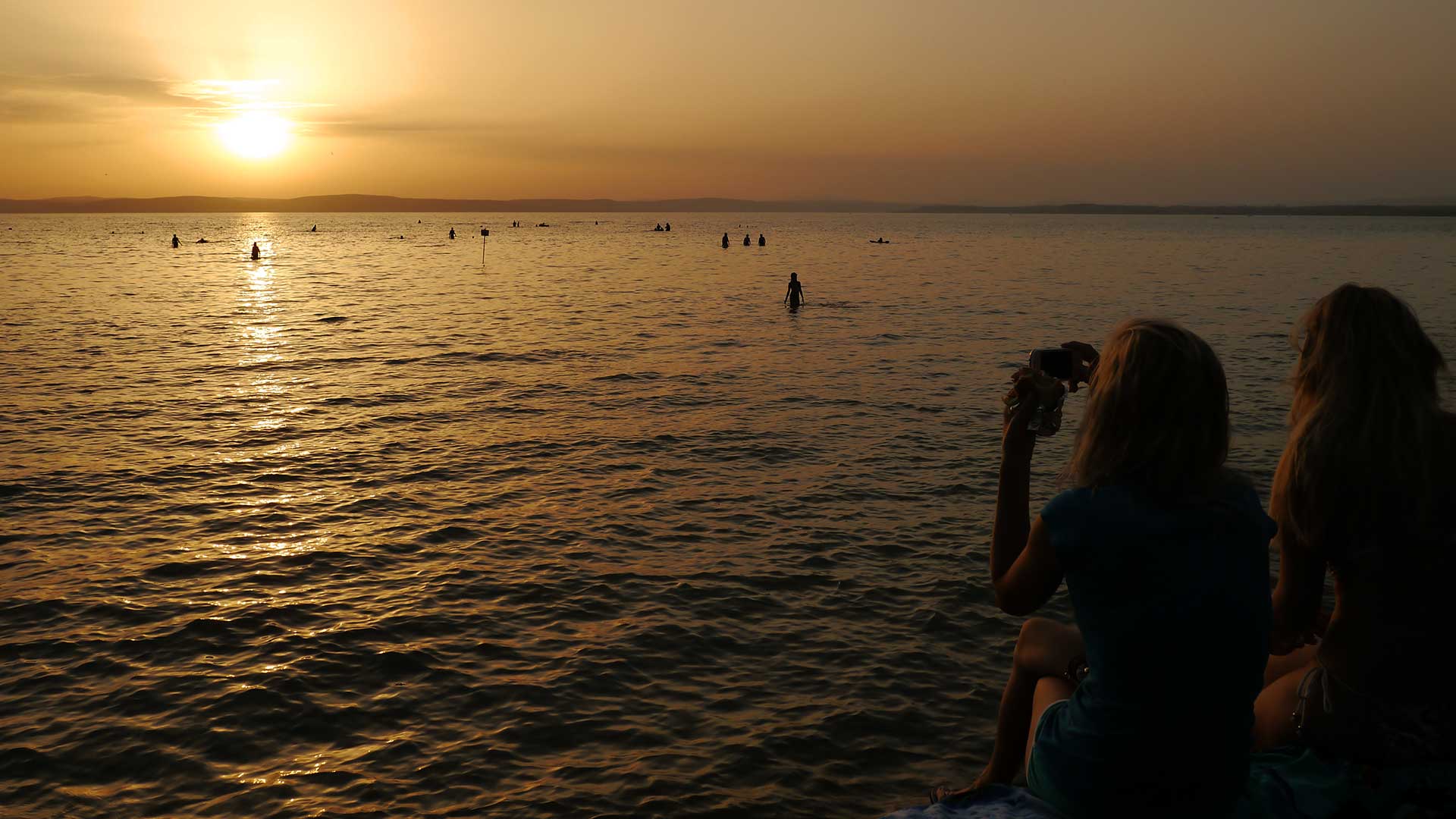 Gyönyörködés a lemenő nap fényében a Balaton déli partján, közvetlen a vízparton